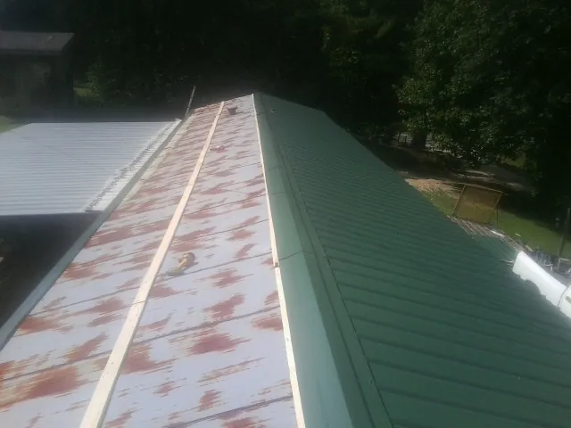 Old rusted panels beside newly installed green metal roofing — Wind Damage Roof Repair by Roofing Brothers in Clarendon