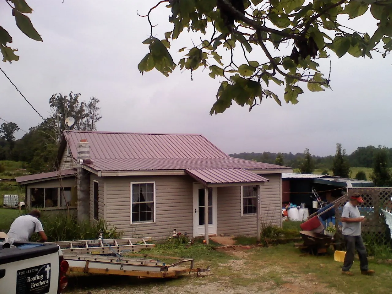 Crew finishing a mauve metal roof on a small farmhouse in Clarendon