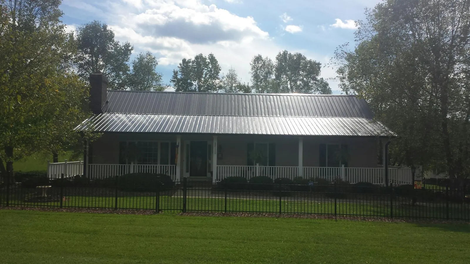 Gray metal roof on a brick ranch with a full width front porch — Gutter Guard Installation work by our crew in Clarendon